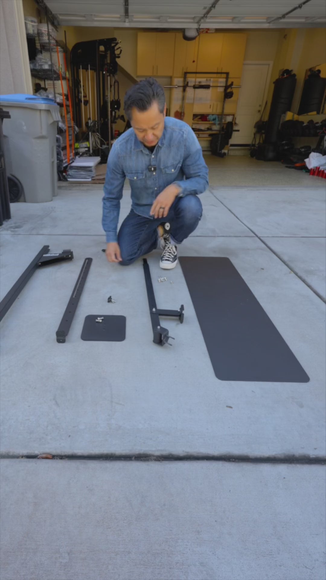 Manual Trash Compactor - Eco-Friendly Outdoors shown in unassembled parts on driveway. Includes metal frame, base plate, and hardware for setup.